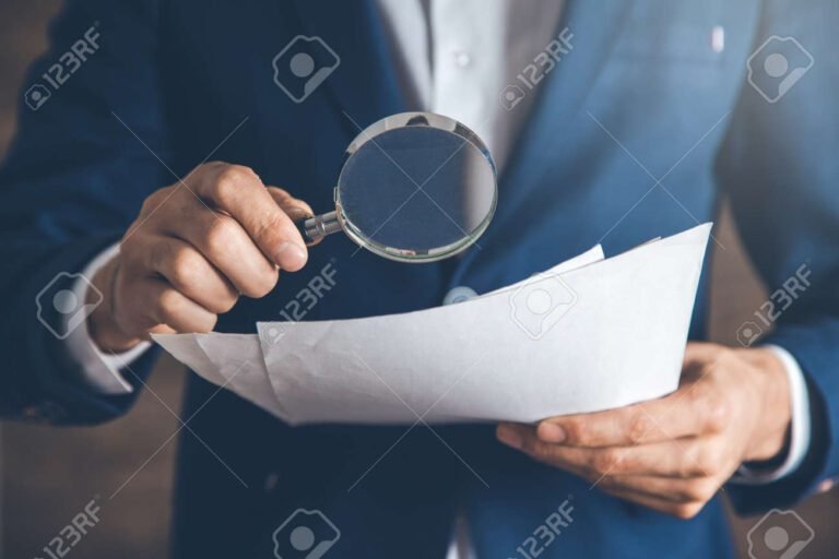 maos segurando uma lupa sobre documentos