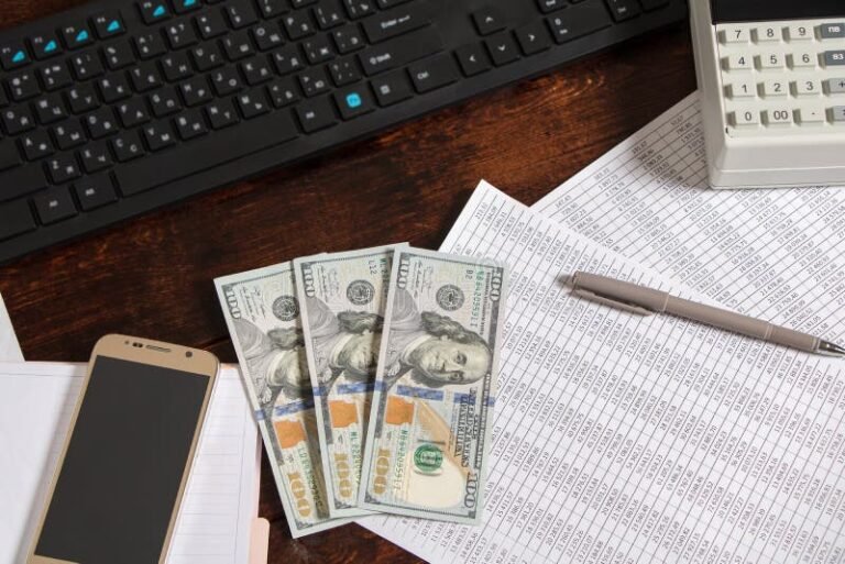 telefone e computador ao lado de documentos